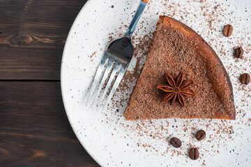 Slice of chocolate curd casserole on a plate, a portion piece of cake with chocolate and coffee. Dark wooden rustic background. top view copy space
