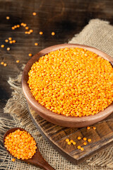 Red lentils in a wooden bowl on a brown wooden table	