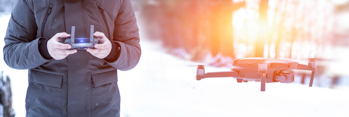 The quadcopter is flying, close-up, a young man with a control panel in his hands. Frosty morning...