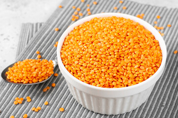 Red lentils in a white bowl on a light gray kitchen table	
