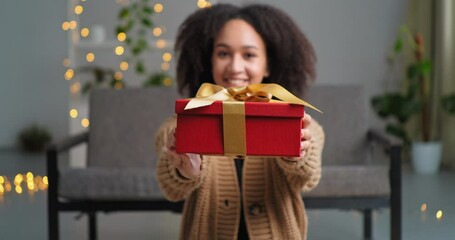 Smiling generous african american woman attractive girl sitting on floor at home giving red gift box congratulating happy birthday anniversary holding present to camera offers parcel, party concept