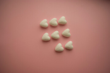 Fototapeta na wymiar Small voluminous white hearts lie on a pink background in three rows and one heart is missing