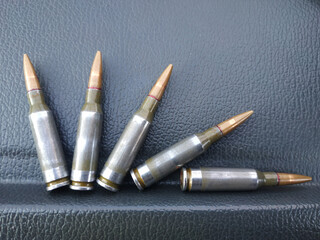Five cartridges from a Kalashnikov assault rifle are photographed in close-up.