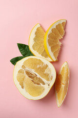 Half of pomelo fruit, slices and leaves on pink background