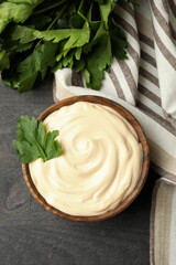 Bowl with mayonnaise, parsley and towel on dark background