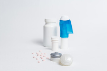 Eye drops bottle and contact lenses container placed on white background with pills in studio 