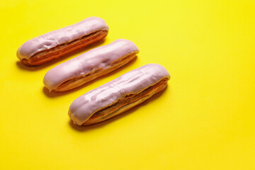 Delicious eclairs with custard on yellow background