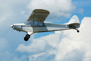 Sport airplane soaring in blue sky in sunny day.