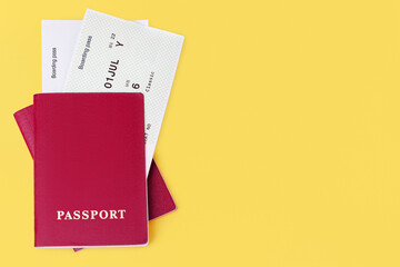 Two red passports, flight boarding passes yellow background close up top view, airline tickets, airplane travel concept, passenger control, summer holidays, vacation, international tourism, copy space