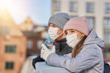 Fototapeta premium Adult couple jogging in the city in masks during lockdown