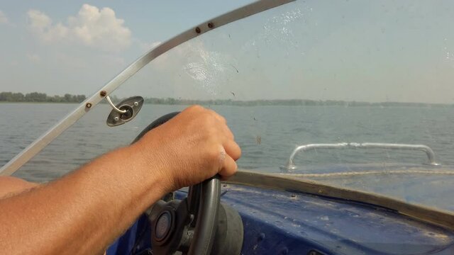 Hands of a man on the steering wheel of a motor boat or boat. A man drives a boat
