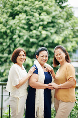 Group of happy Asian mature Vietnamese friends standing outdoors and smiling at camera