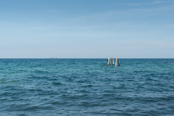 an old wooden poles with blue sky on the sea.