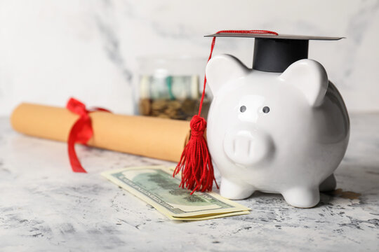 Piggy bank with graduation hat and money on light background