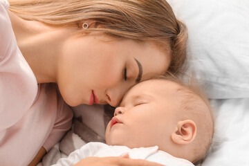 Mother with cute little baby sleeping on bed