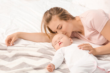 Mother with cute little baby sleeping on bed