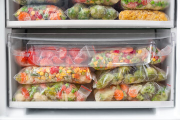 Plastic bags with frozen vegetables in refrigerator