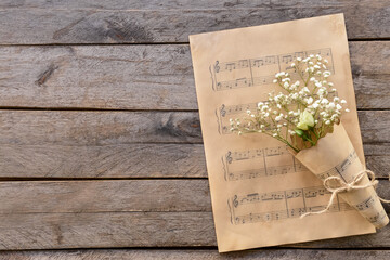 Music sheets and flowers on wooden background