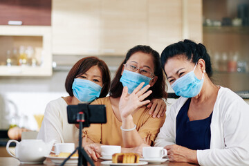 Group of senior Asian women in medical masks recording video for subscribers or video calling...