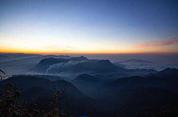 Fototapeta na wymiar Sunrise over the mountains standing in fog on the island of Sri Lanka.