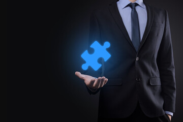 Businessman holds a piece of puzzle jigsaw in his hands.The concept of cooperation, teamwork, help and support in business.