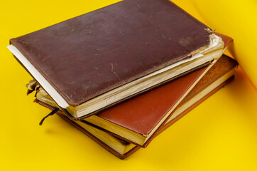 Stack of old diaries lying on yellow background.