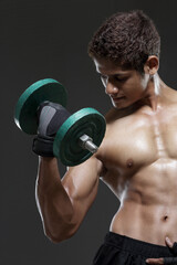 Fototapeta na wymiar muscular young man lifting weights for biceps curl on grey. 