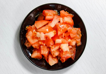 Ripe tomatoes on a plate, which are finely chopped.