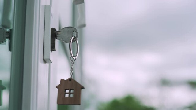 The house key for unlocking a new house is plugged into the door. The wooden keychain was moving as the wind blew. Ready-to-live house concept