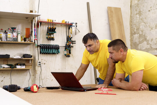 Carpenters using laptop in workshop, searching for a solution