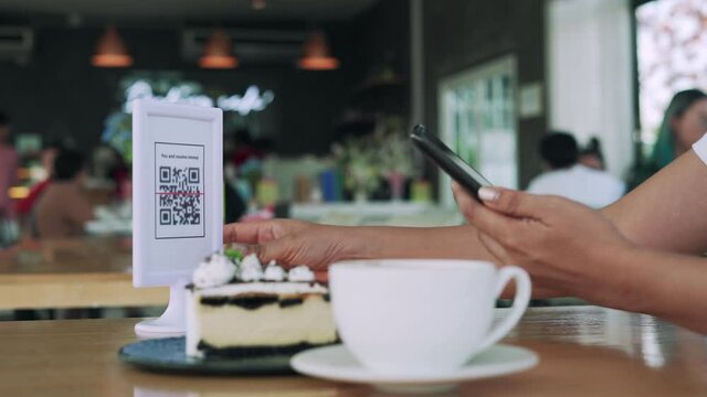 Women's hands are using  the phone to scan the qr code to select food menu. Scan to get discounts or pay for food. The concept of using a phone to transfer money or paying money online without cash.