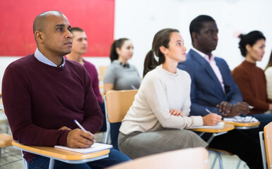 Fototapeta premium Multiethnic group of young people studying together at tables in classroom