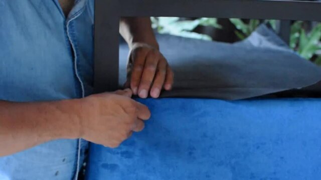 hands of an upholsterer arranging and stapling the fabric with an air staple gun