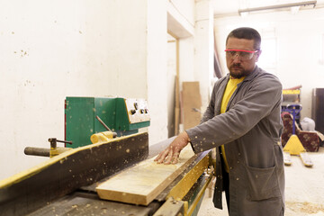 Male carpenter using saw for cutting wood at workshop