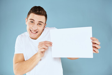man holding a sheet of paper in his hands white t-shirt cropped view blue background