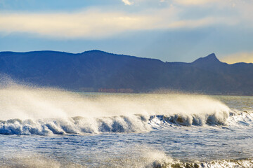 Sea waves forming white foam on sunny day.