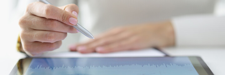Female hand holds stylus over included tablet with business records. Business applications concept