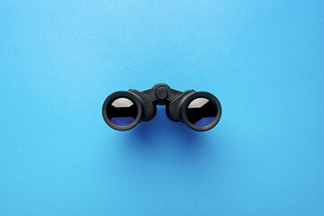 Binoculars on a light blue background. Banner. Flat lay, top view