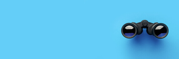Binoculars on a light blue background. Banner. Flat lay, top view