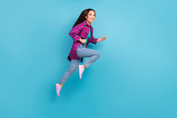 Fototapeta na wymiar Full size profile photo of attractive lady running fast wear purple checkered long shirt isolated on blue color background