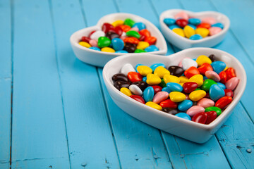 Multicolored candies in a plate in the shape of a heart .