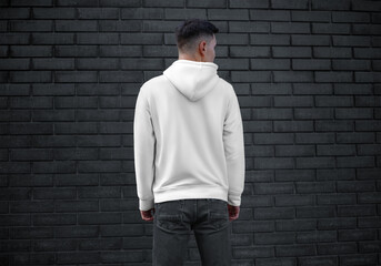 Long sleeve white mens clothing template on young guy on brick wall background, back view, blank...