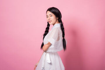 Happy cheerful young woman wearing her black hair rejoicing at positive news or birthday gift, looking at camera with joyful and charming smile. Asian girl portrait on pink background in studio