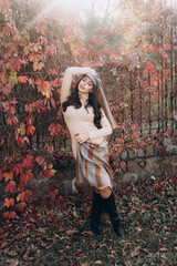 Beautiful and stylish girl model with makeup in a beige dress and a scarf in the form of plaid in the park