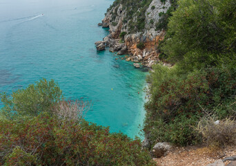 Fototapeta na wymiar View over Gulf of Orosei with limestone cliffs, green bushes, white beach and turquoise blue water. Famous travel touristic destination in Sardinia island, Italy.