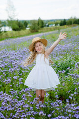 little girl in a straw hat in a purple field in summer