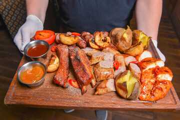 Close up of delicious mixed grilled platter. Meat, steaks, sausages, potatoes served in a restaurant or diner.