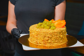 Whole Cake Napoleon served by waiter in cafe or restaurant. Birthday party celebration, eating out concept, service.