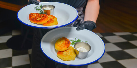 Cheesecakes with sour cream served by waiter in cafe or restaurant. Delicious meal for dinner or supper.