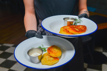Cheesecakes with sour cream served by waiter in cafe or restaurant. Delicious meal for dinner or supper.